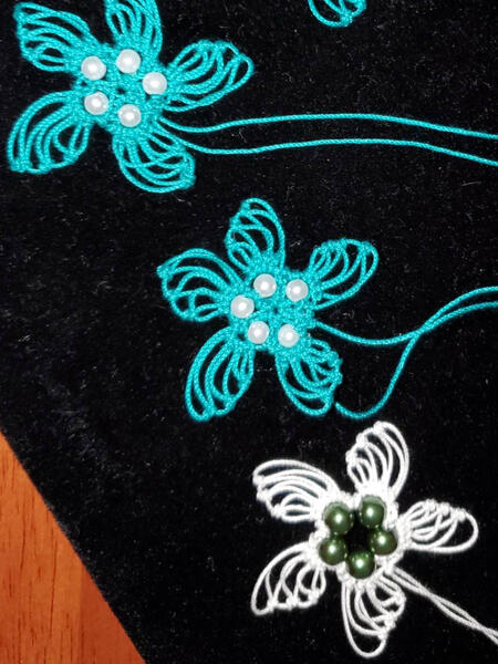 Joan is making lace flower earrings with beads.